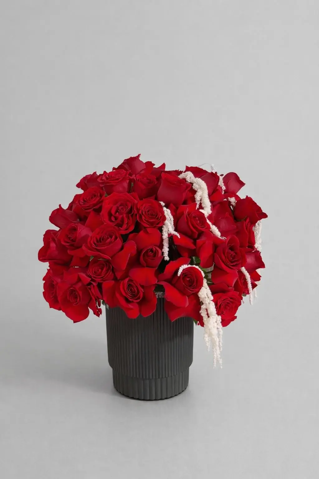 Arreglo de 50 rosas rojas en florero negro elegante